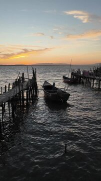 Porto Palafitico in Comporta, Portugal, featuring traditional wooden stilts and rustic fishing boats along the winding pier, capturing the charm of this unique harbor on a calm 