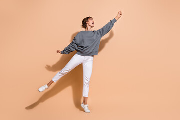 Full size photo of adorable woman dressed grey pullover white pants catch object look empty space isolated on pastel color background