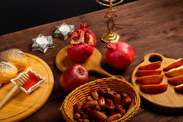 Challah, honey, apple and pomegranate and burning candles on wooden table