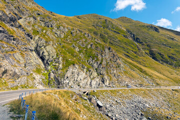 A breathtaking panoramic view of the Carpathian Mountains in Romania, featuring a stretch of the Transfăgărășan Highway winding through the valley. 