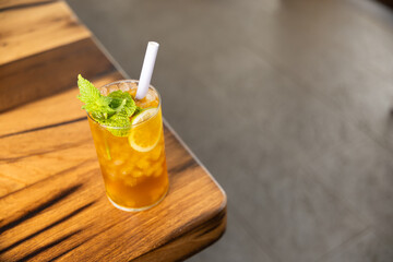 Close-up piña colada tea cocktail with peach balls, orange or lemon slice and mint, non-alcoholic cocktail, refreshing and healthy drink, free background to write, copy space
