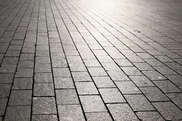 Stone pavement texture, cobbled street in sunlight. Road from tiles for background