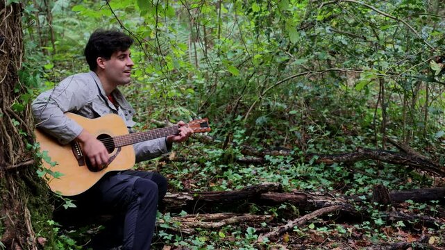 Close-up of a hiker happily playing acoustic guitar in the forest
