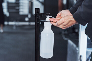 Obraz premium Hands, sanitizer and dispenser in gym for health, germ protection or safety as athlete or trainer. Person, care and wellness in fitness center or sports club for hygiene, clean or illness prevention
