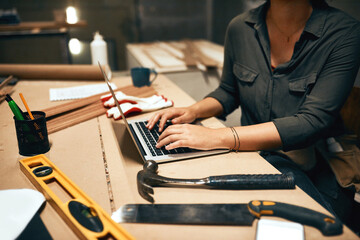 Woman, hands or laptop in workshop for carpentry, design process or research at night. Woodworker,...