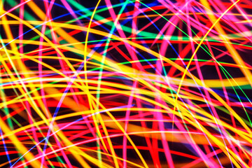 Abstract blurred lights creating glowing bokeh. Christmas fair with neon colors and long exposure light trails. Unique design concept with glowing bulbs in motion. Vibrant, artistic modern background.