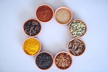 Spices, bowl and selection of herbs seasoning on studio background for cooking or top view mockup space. Circle, organic condiments and flavor ingredients with curry powder, masala and ground pepper