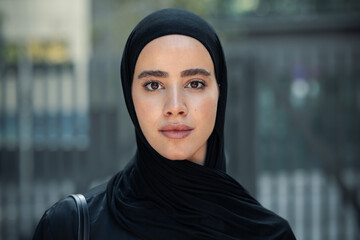 Confident serious woman with hijab standing looking at camera in the city