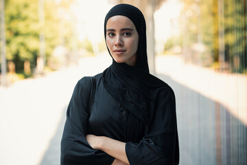 Confident serious woman with hijab standing looking at camera in the city