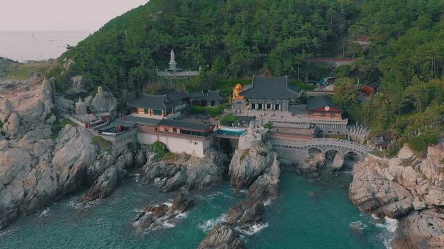 BUSAN, SOUTH KOREA - OCTOBER 19, 2024: Aerial view of coastal temple complex showcasing scenic cliffs and serene waters