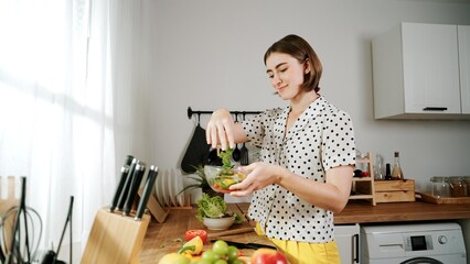 Caucasian mother put vegetable in bowl making a salad for breakfast while happy mom preparing fresh ingredients for salad at modern kitchen. House keeper cooking healthy meal. Care concept. Pedagogy.