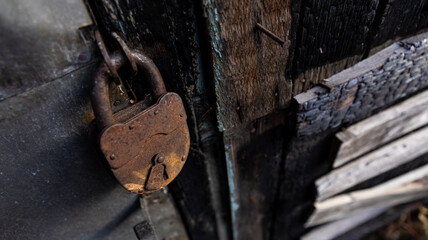 A rusty padlock is currently hanging on an old wooden door