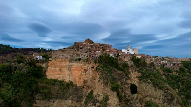 4K Aerial drone video of ancient town elevated in the hills with unreal cloud shapes with a mystical look. Abandoned ghost town Tursi in Italy outback with empty houses and streets