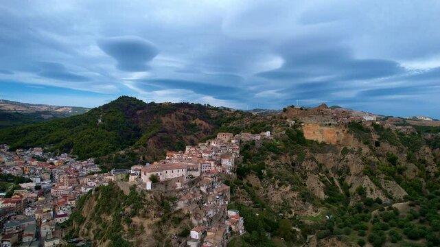 4K Aerial drone video of ancient town elevated in the hills with unreal cloud shapes with a mystical look. Abandoned ghost town Tursi in Italy outback with empty houses and streets