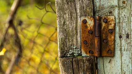 Here is a closeup image of a rusty door hinge attached to a wooden post