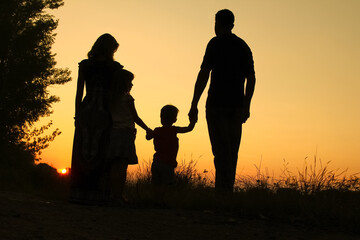 silhouette of a happy family on the nature of the sunset in the park