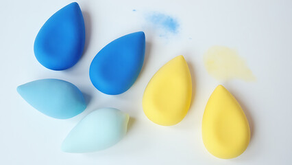 Blue violet and yellow makeup sponges in a stylish arrangement on a clean white surface.