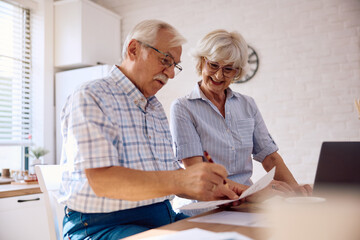 Happy retired couple going through their financial bills at home.