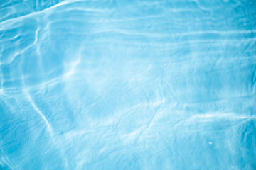 Blue water with ripples on the surface. Defocus blurred transparent blue colored clear calm water surface texture with splashes and bubbles. Water waves with shining pattern texture background.