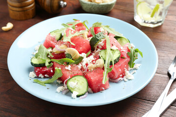 Tasty salad with watermelon, feta cheese, cashews and arugula on wooden table