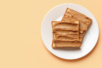 Delicious sandwiches with peanut butter on pale orange table, top view. Space for text