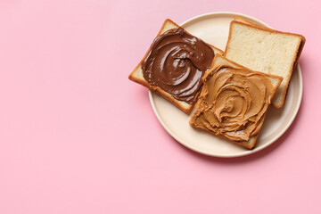 Delicious sandwiches with peanut butter and chocolate paste on pink table, top view. Space for text