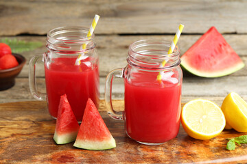 Tasty watermelon drink in mason jars and fresh fruits on wooden table, closeup