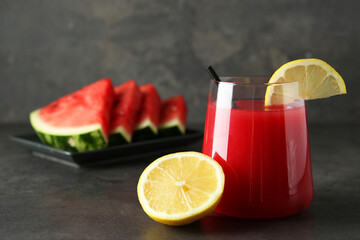 Delicious watermelon drink in glass and fresh fruits on dark grey table