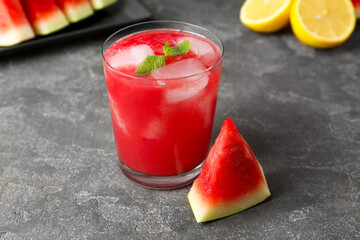 Tasty watermelon drink in glass, fresh fruits and mint on grey table, closeup