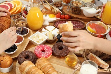 Women eating different food during brunch at wooden table, closeup