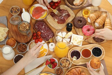 Women eating different food during brunch at wooden table, closeup