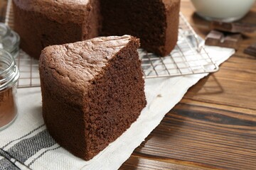 Piece of tasty chocolate sponge cake on wooden table, closeup