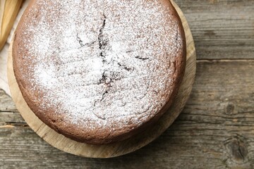 Tasty chocolate sponge cake with powdered sugar on wooden table, top view