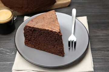 Piece of tasty chocolate sponge cake served on wooden table, closeup