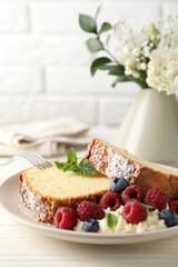 Freshly baked sponge cake, whipped cream, berries and mint on white wooden table, closeup