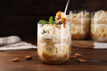 Taking tasty trifle dessert at wooden table, closeup