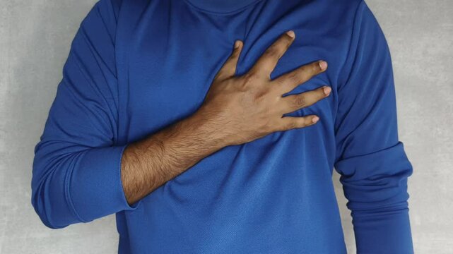 Young adult man touching chest with his hand while having a heart attack, stroke, thoracic osteochondrosis, panic or anxiety attacks. Sudden heart pain, ache, soreness, stress and discomfort concept.