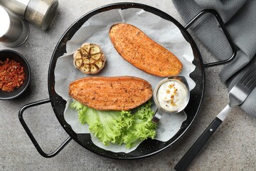 Tasty cooked sweet potato in baking dish served on grey textured table, flat lay
