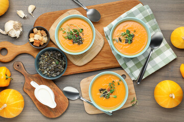 Delicious pumpkin soup served on wooden table, flat lay