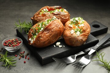 Tasty cooked sweet potatoes with feta cheese, green onion and parsley served on gray textured table, closeup