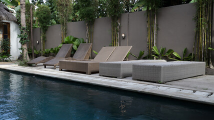 Poolside Lounge Area with Wicker Sunbeds and Tropical Bamboo Wall in Serene Villa Setting