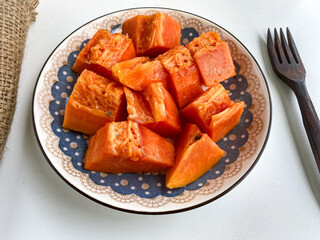 a top view of plate of diced papaya.  Chopped papaya fruit in a plate on a white background.