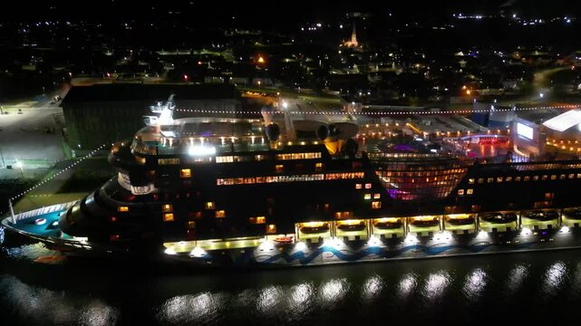cruise ship docked moored port invergordon night illuminated vessel stands out against dark waters creating slow side drone shot aerial travel holiday adventure harbor scenic nature 