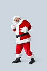Funny Santa Claus dancing on grey background