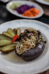Blood Sausage with sautee onions and pickles on a plate
