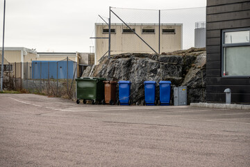 Row of trash bins by a parking lot.