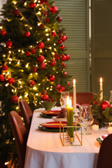 Festive table setting with Christmas decorations and burning candles in dining room