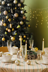 Festive table setting with Christmas decorations, reindeers and burning candles in dining room