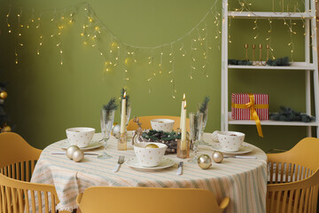 Festive table setting with Christmas decorations, reindeers and burning candles in dining room
