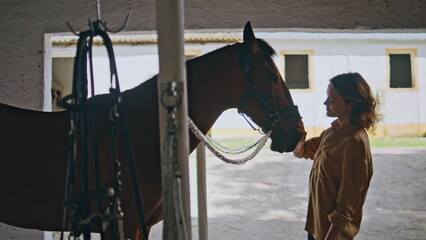 Calm lady petting equine in ranch closeup. Happy horse woman owner in paddock